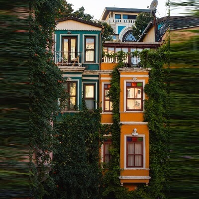 In this example, we switch to a custom orientation mode and set the proportions of the new JPEG to a square. The original JPEG picture of multi-colored houses wrapped in vines has a vertical orientation and we set the new dimensions to 400 by 400 pixels. We select the "Stretch Edges" method with a depth of 10 pixels, which makes our algorithm take stripes of 10 pixels from the right and left sides of the picture and stretch them to fill a square area for the new photo. (Source: Pexels.)